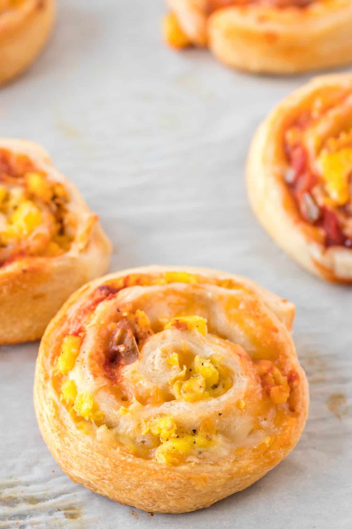 Golden baked breakfast pinwheels on a parchment-lined baking sheet, ready to serve.