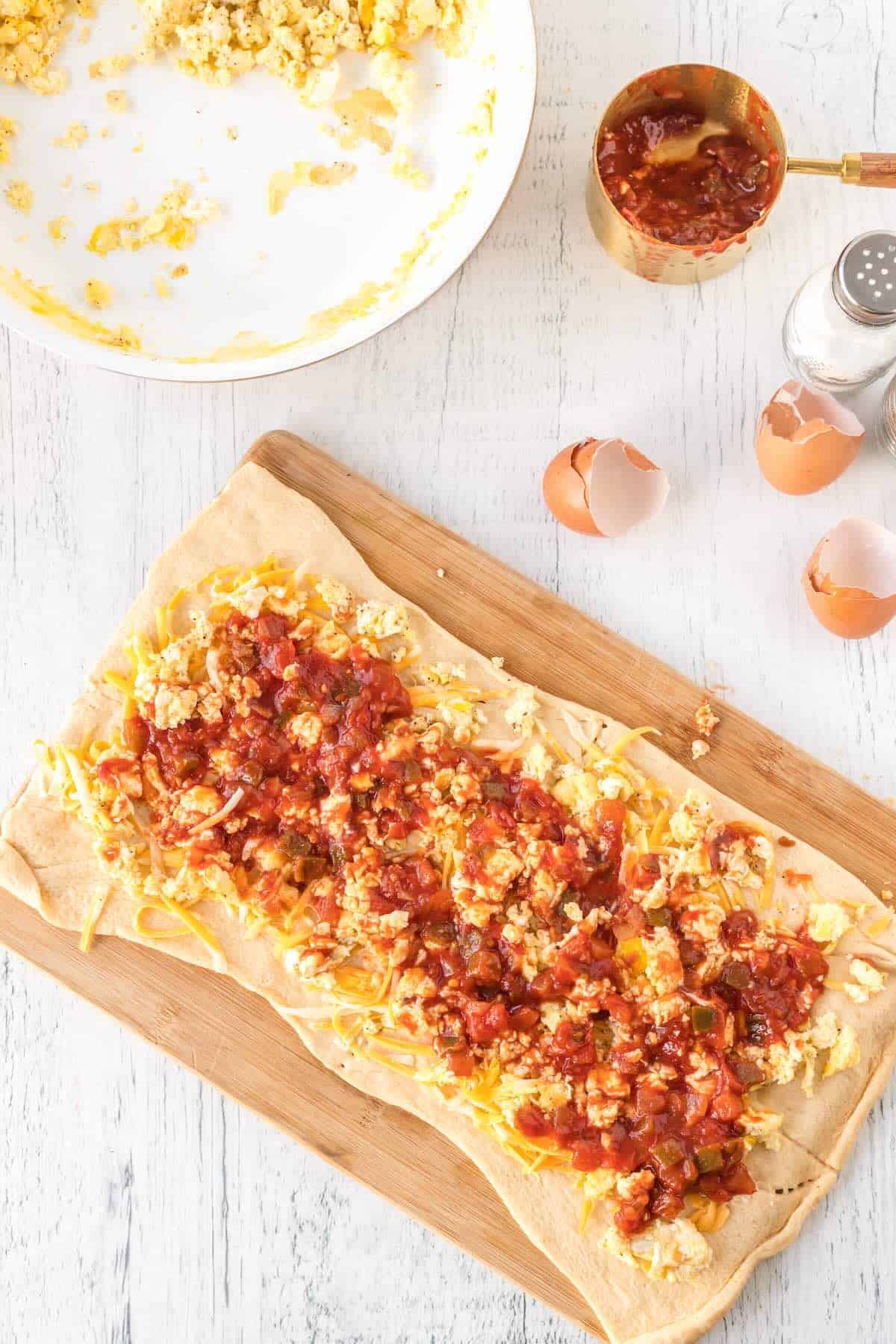 Scrambled eggs, shredded cheese, and salsa spread over crescent dough before rolling.
