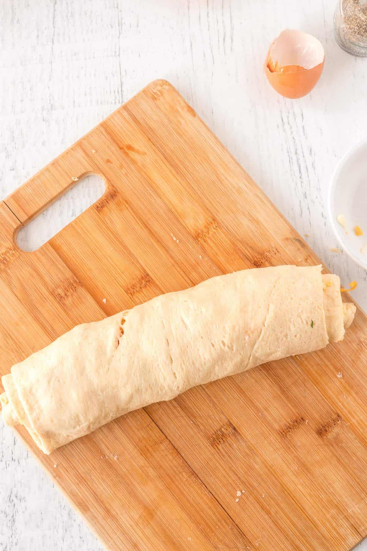 Crescent dough rolled with egg, cheese, and salsa filling, ready to slice.