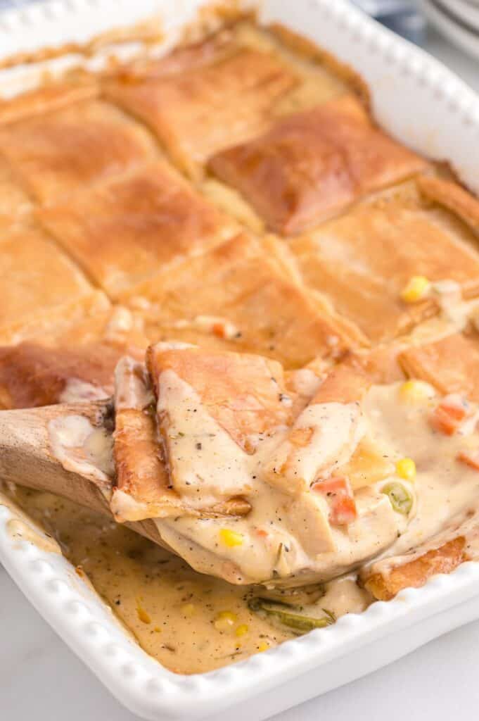 Close-up of creamy chicken pot pie filling with vegetables and flaky puff pastry topping.