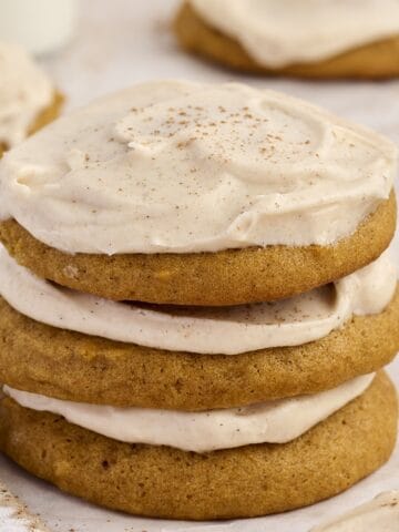 Stack of soft pumpkin cookies with cream cheese icing.