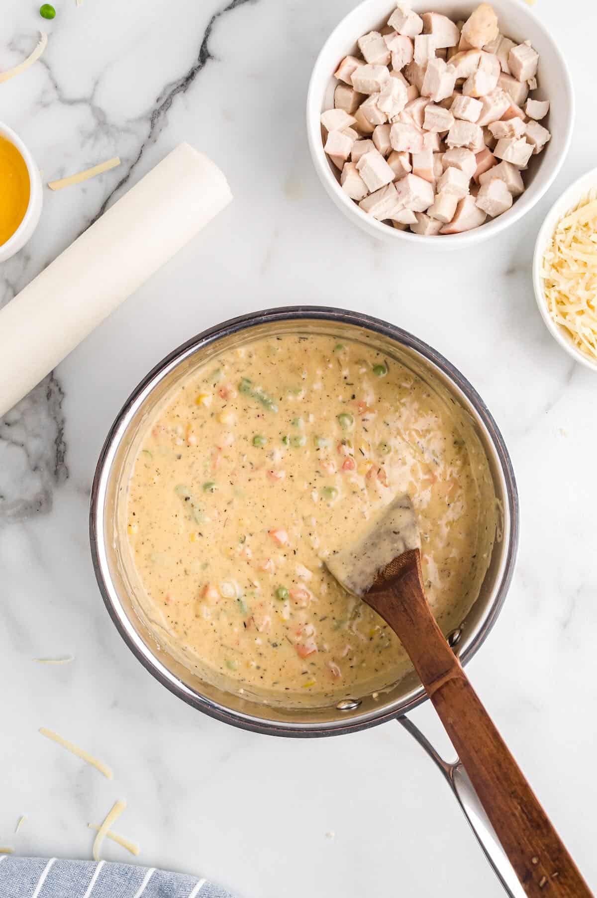 Whisking flour, spices, chicken stock, and cream together to make the pot pie sauce.