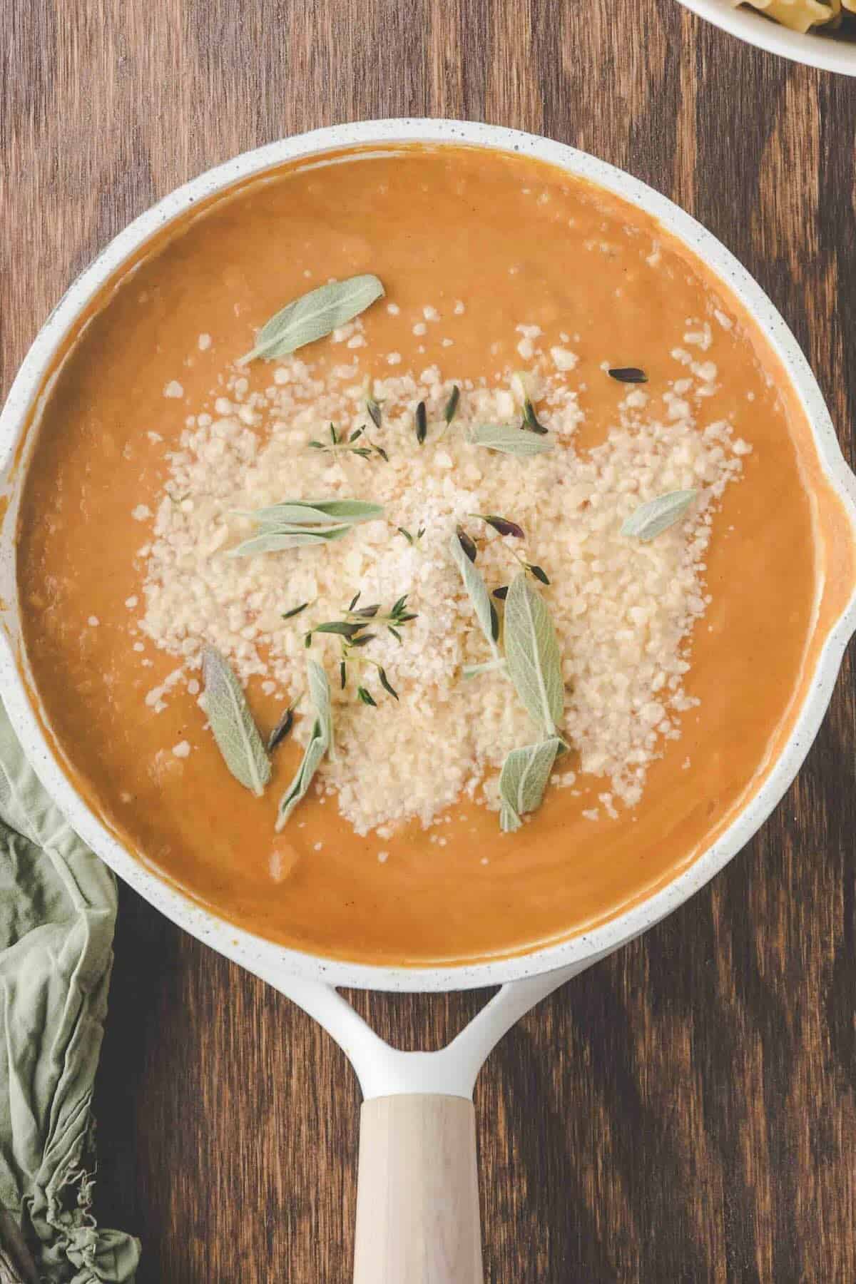 Stirring Parmesan cheese and lemon juice into creamy pumpkin pasta sauce.