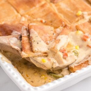 A spoonful of creamy chicken pot pie topped with puff pastry.