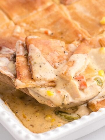 A spoonful of creamy chicken pot pie topped with puff pastry.