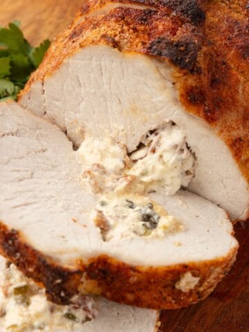 Sliced stuffed pork loin served for dinner with cheesy filling visible in each piece.