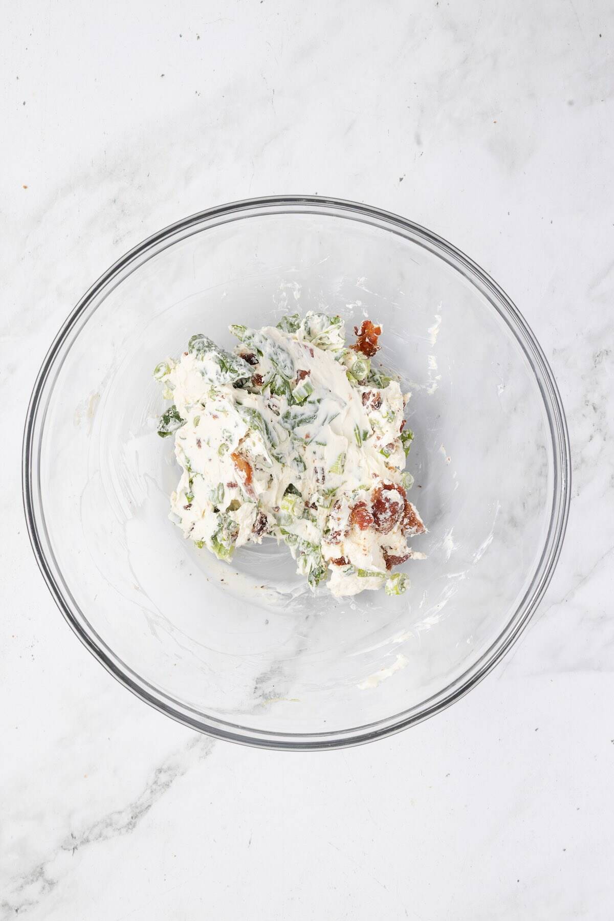Cream cheese, spinach, cheddar, bacon, and green onions mixed together in a bowl.