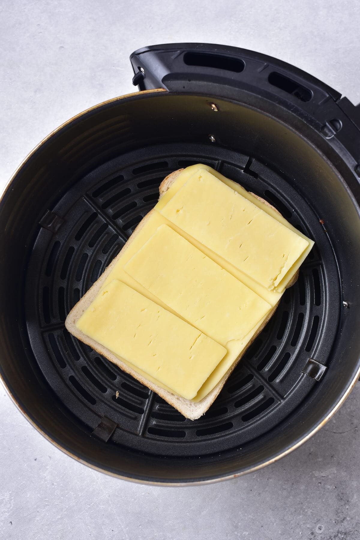 Layers of cheddar cheese placed on bread before air frying.