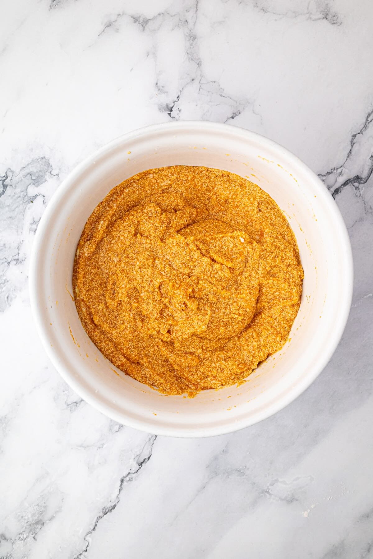 Adding mashed banana and pumpkin puree into banana bread batter.