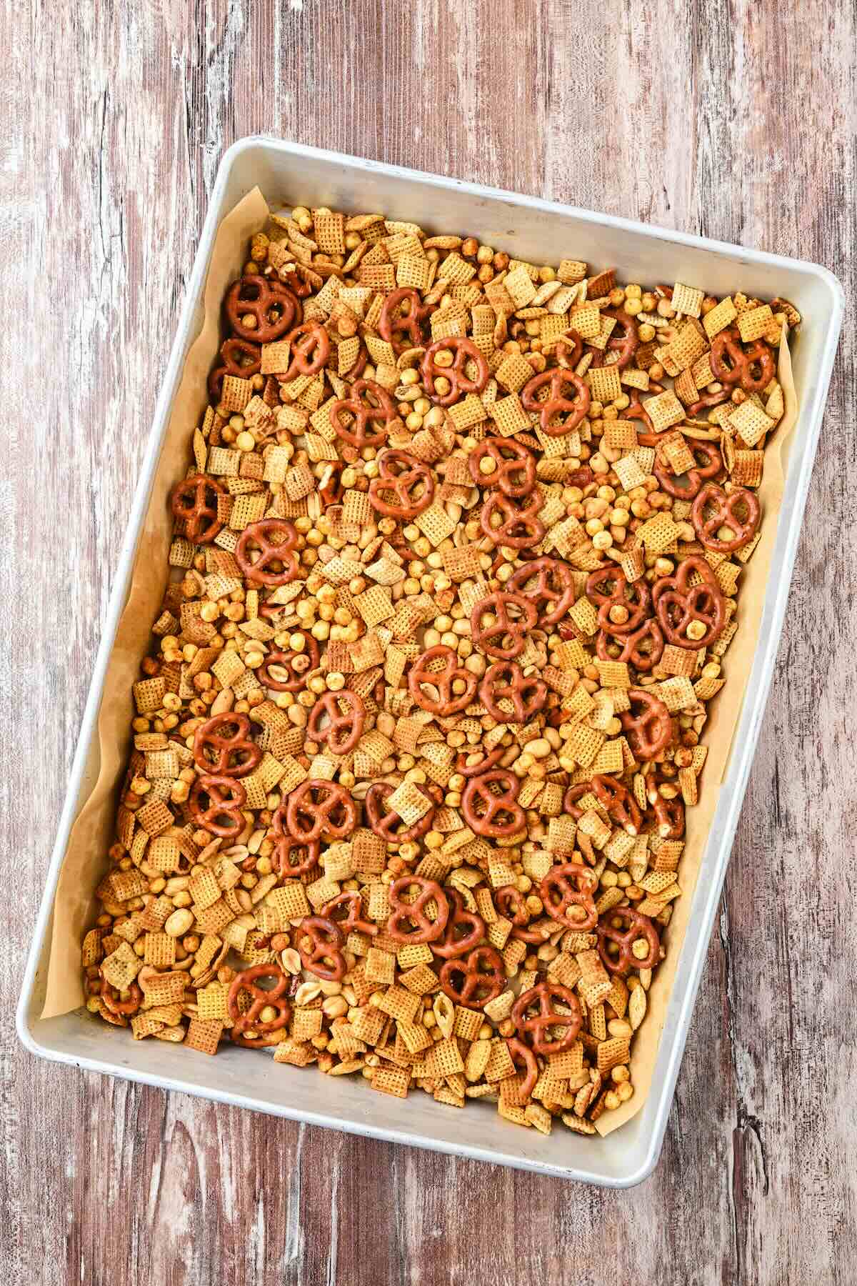 Freshly baked Chex Mix cooling on a baking sheet before storing.