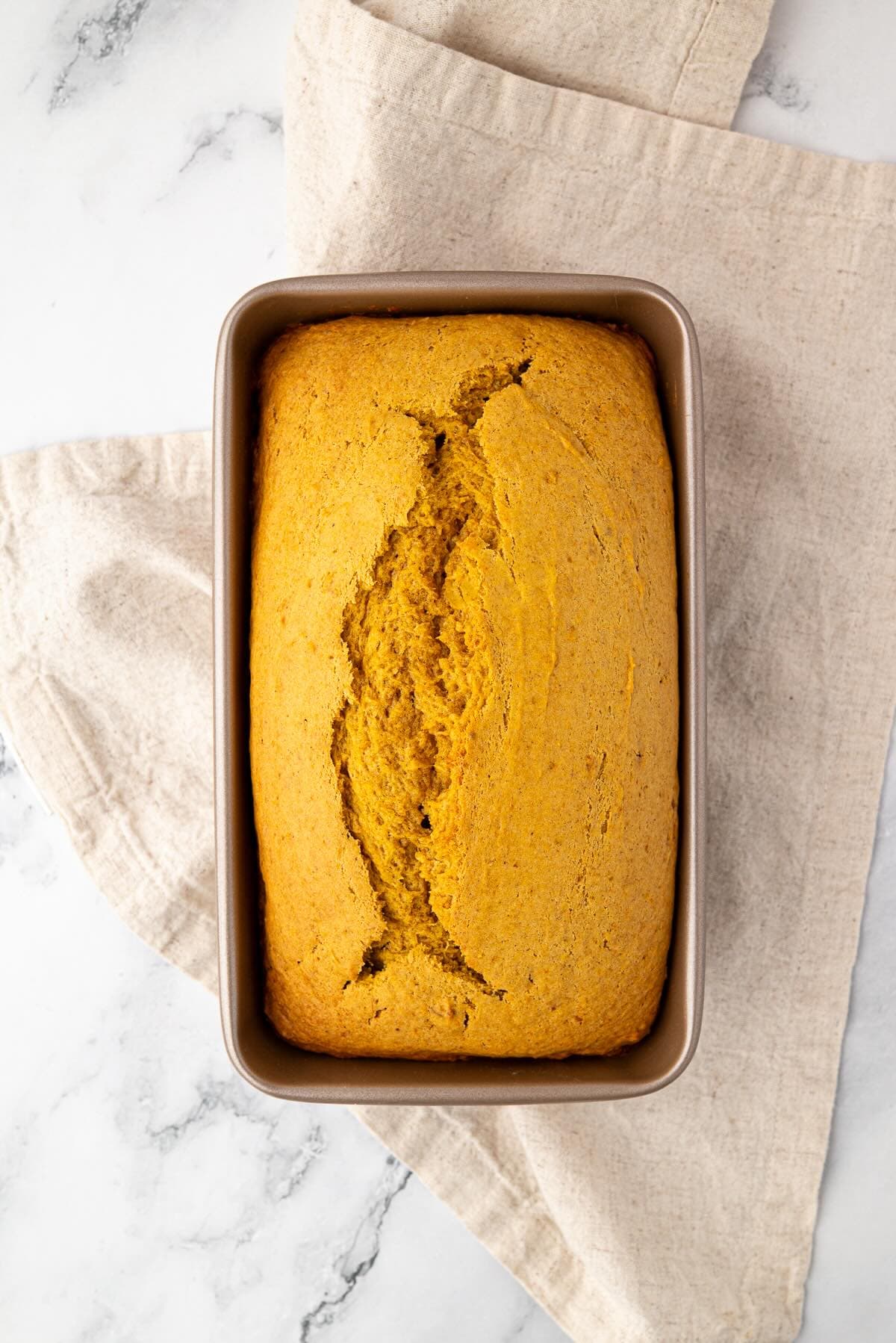 Golden baked pumpkin banana bread cooling in the loaf pan after baking.