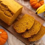 Sliced banana bread with pumpkin on a cutting board.