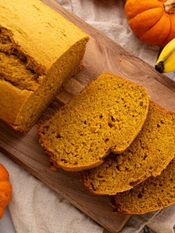 Sliced banana bread with pumpkin on a cutting board.