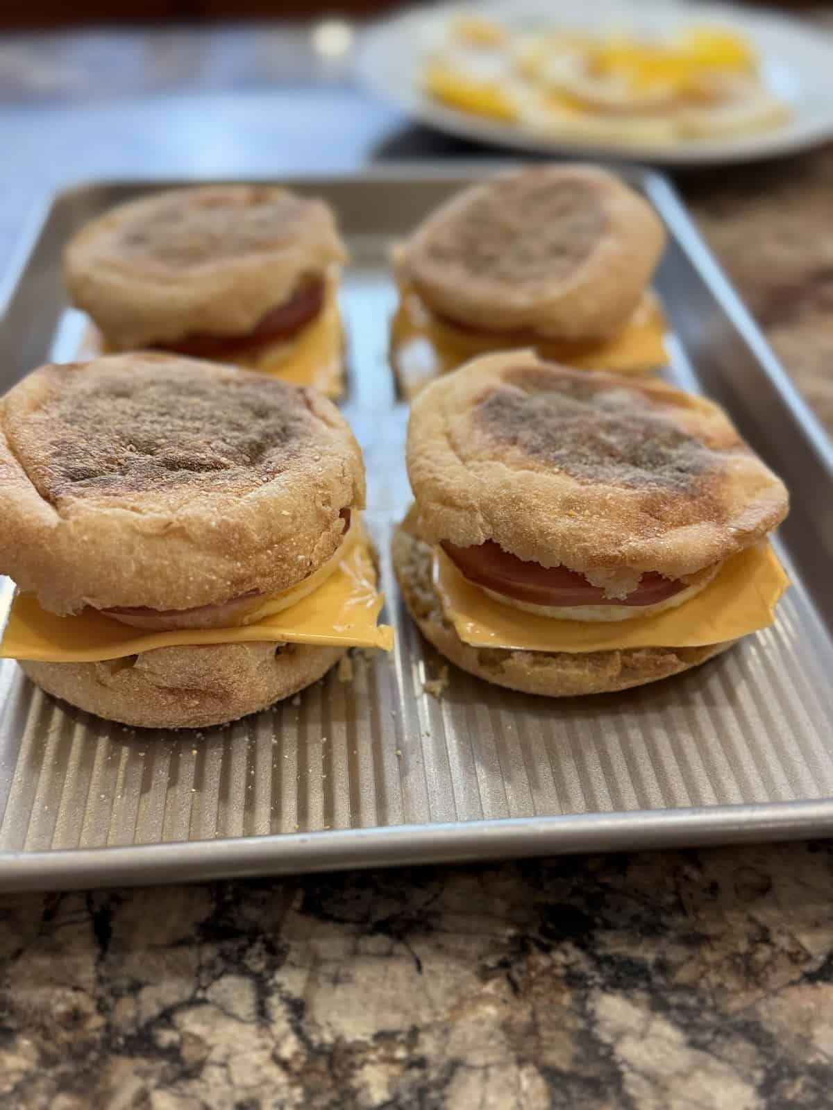 A tray of homemade egg breakfast sandwiches on English muffins.