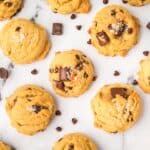 Chewy brown butter sourdough chocolate chip cookies on a cooling rack with melty chocolate chips.