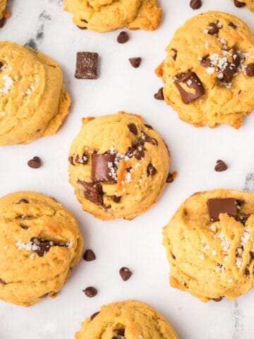 Chewy brown butter sourdough chocolate chip cookies on a cooling rack with melty chocolate chips.