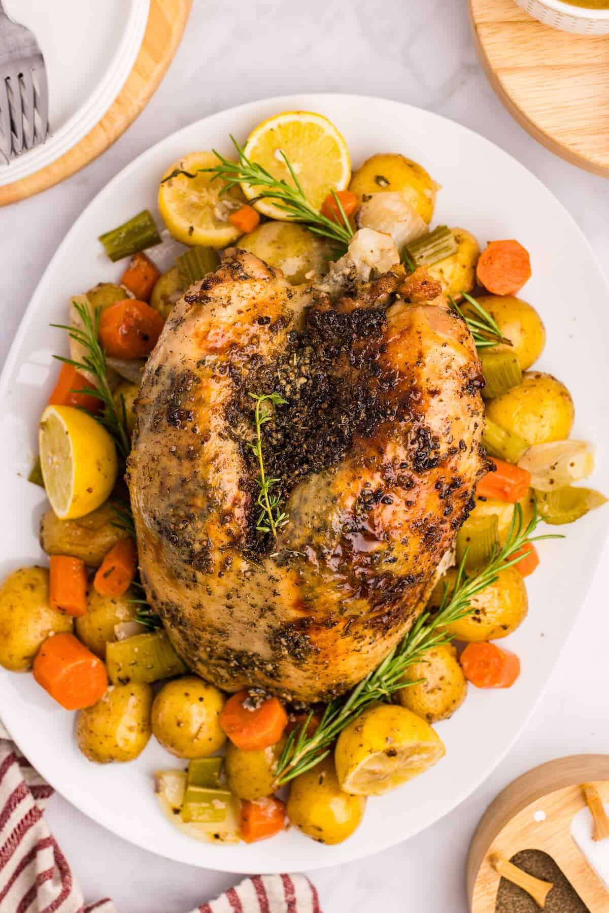 A butter and herb coated roasted turkey breast on a platter for a special dinner.
