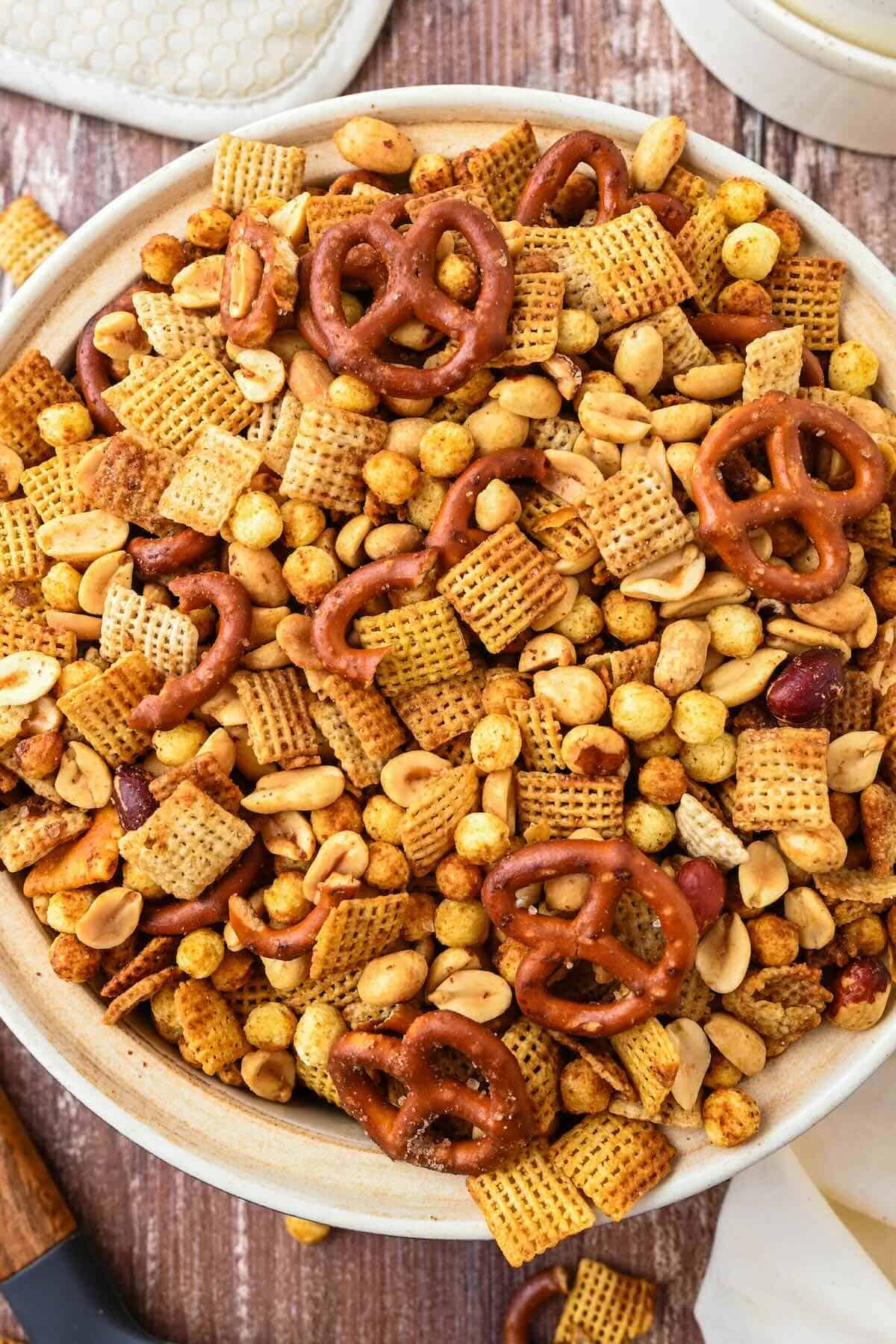 Close-up of crunchy homemade Chex Mix showing cereal, pretzels, and peanuts coated in buttery seasoning.