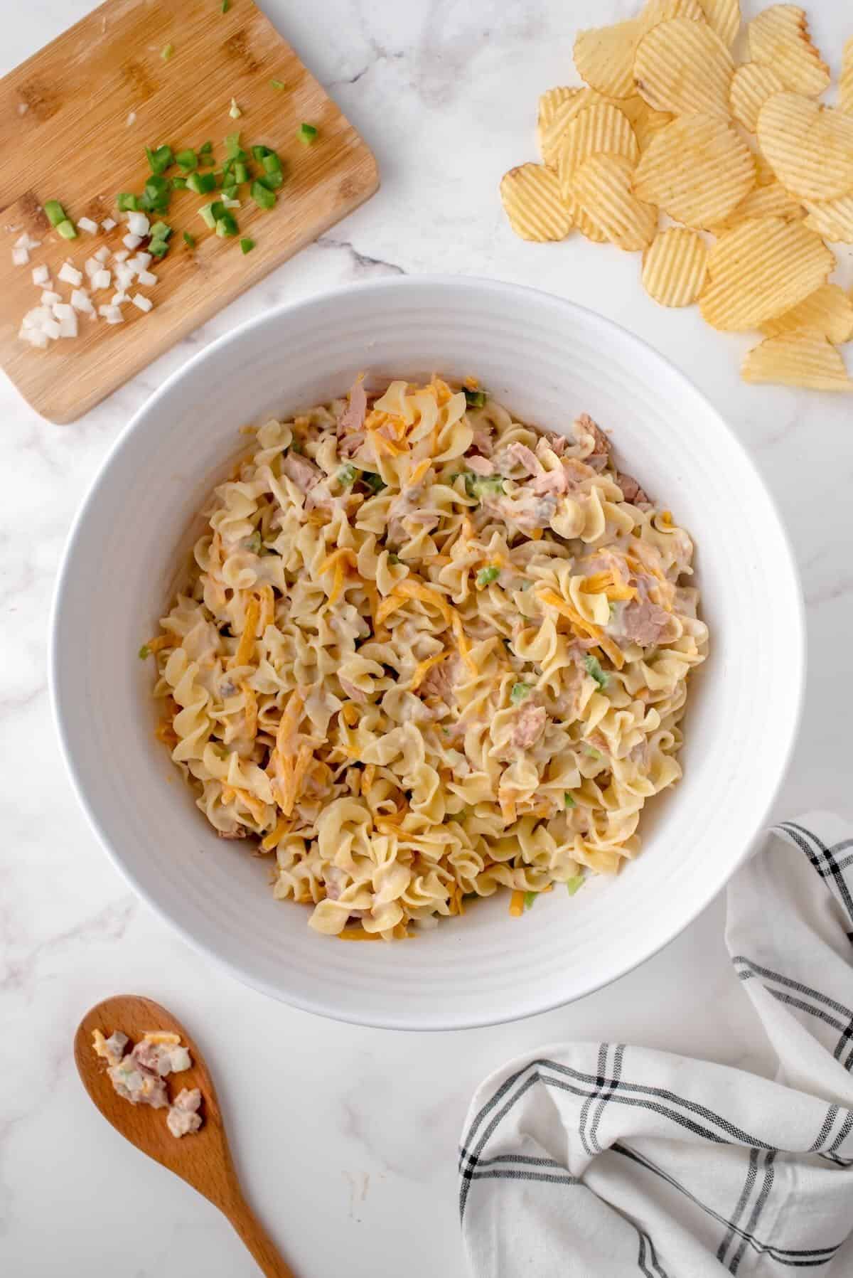 Folding cooked noodles into the creamy tuna mixture.