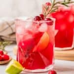 Cranberry lime margarita mocktails served on a holiday table with cranberries and greenery.