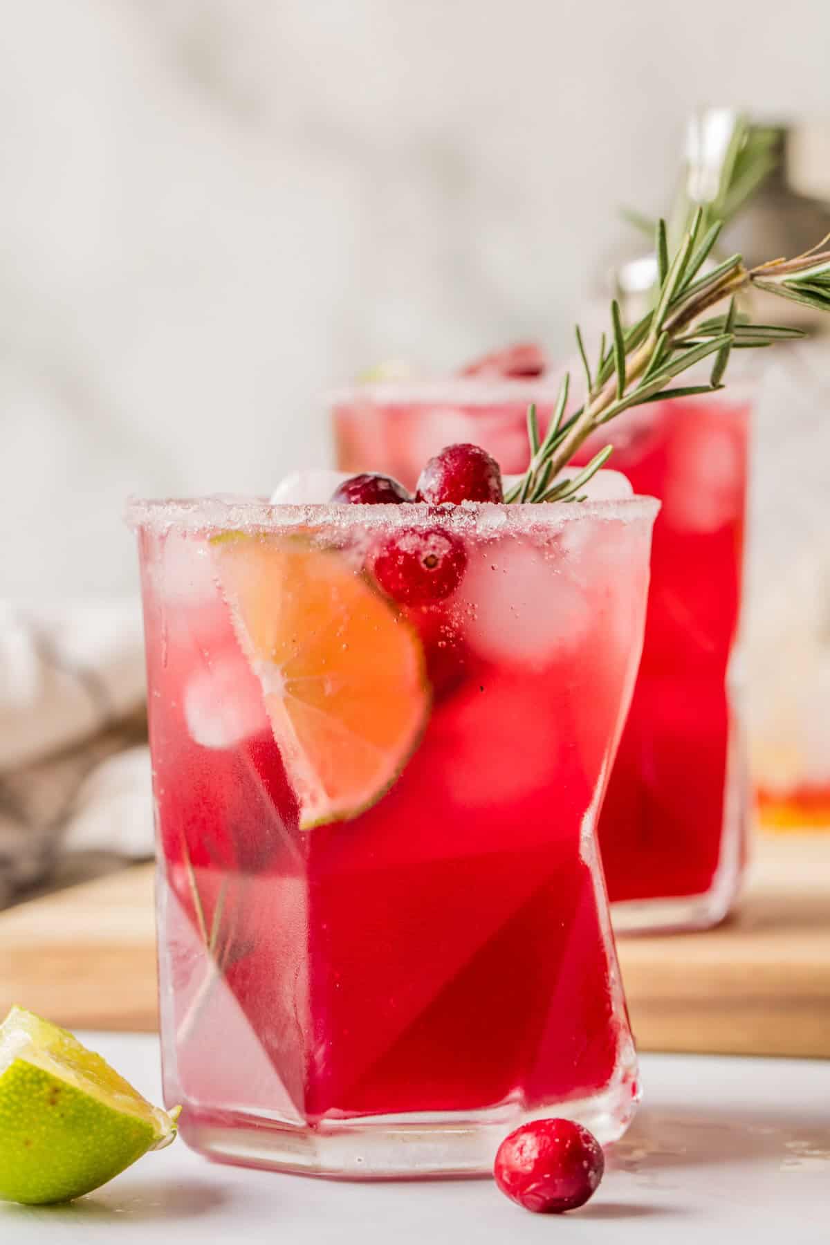 Close-up of cranberry lime margarita mocktail showing sparkling bubbles and festive red color.