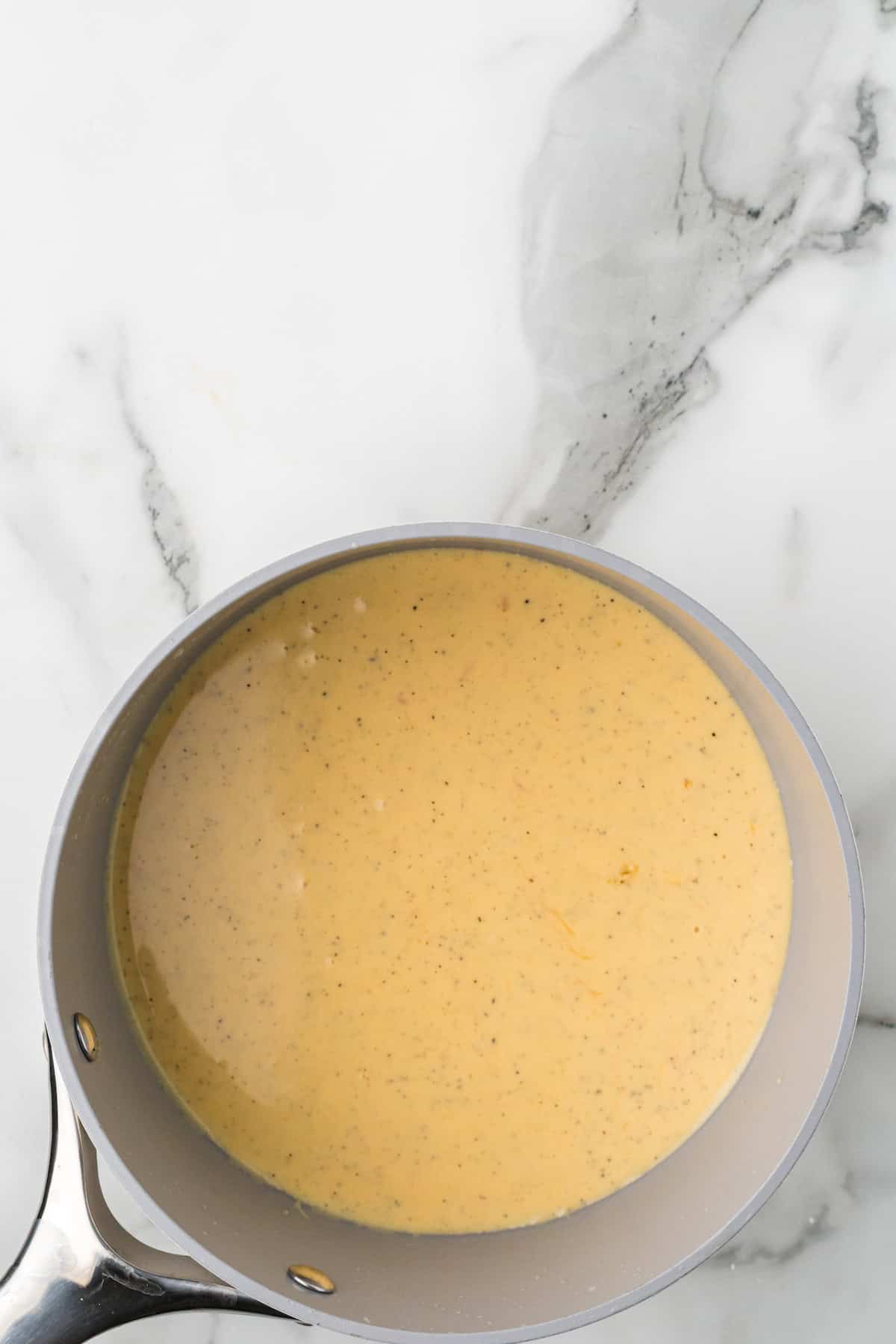 Melting cheddar cheese into the creamy sauce for scalloped potatoes.