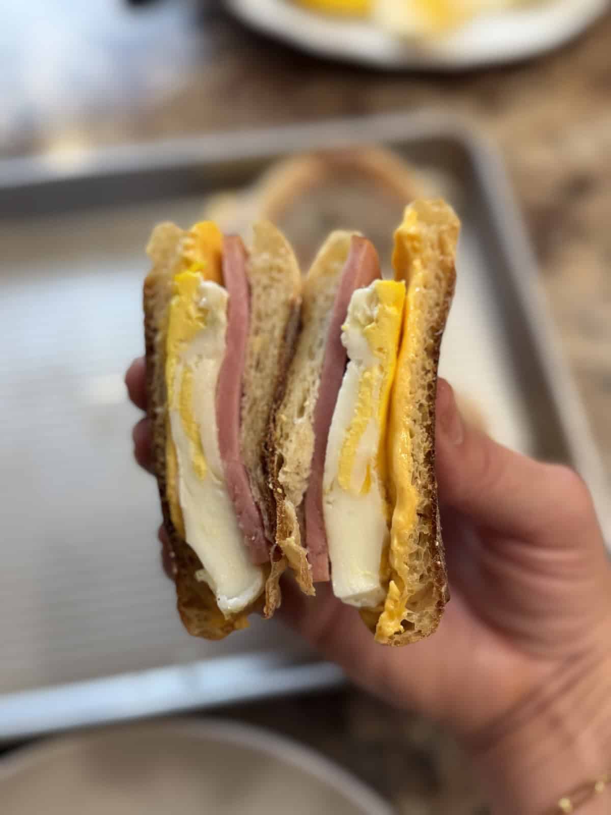 A breakfast sandwich cut in half with egg, ham and cheese.
