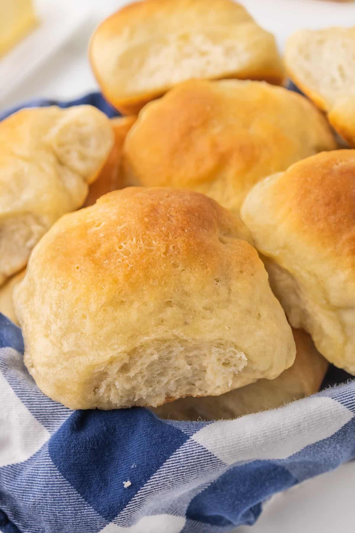 Farm-style yeast dinner rolls resting on a blue checkered towel, ready to share at the dinner table.