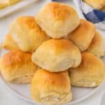 A stack of dinner rolls on a plate.
