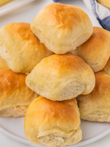 A stack of dinner rolls on a plate.