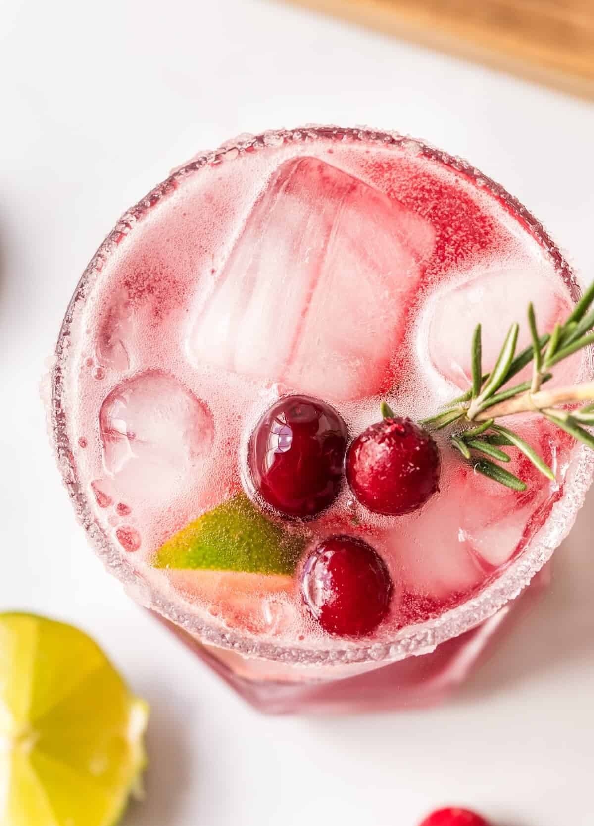 Garnishing a cranberry lime margarita mocktail with a lime wedge and cranberries for the holidays.