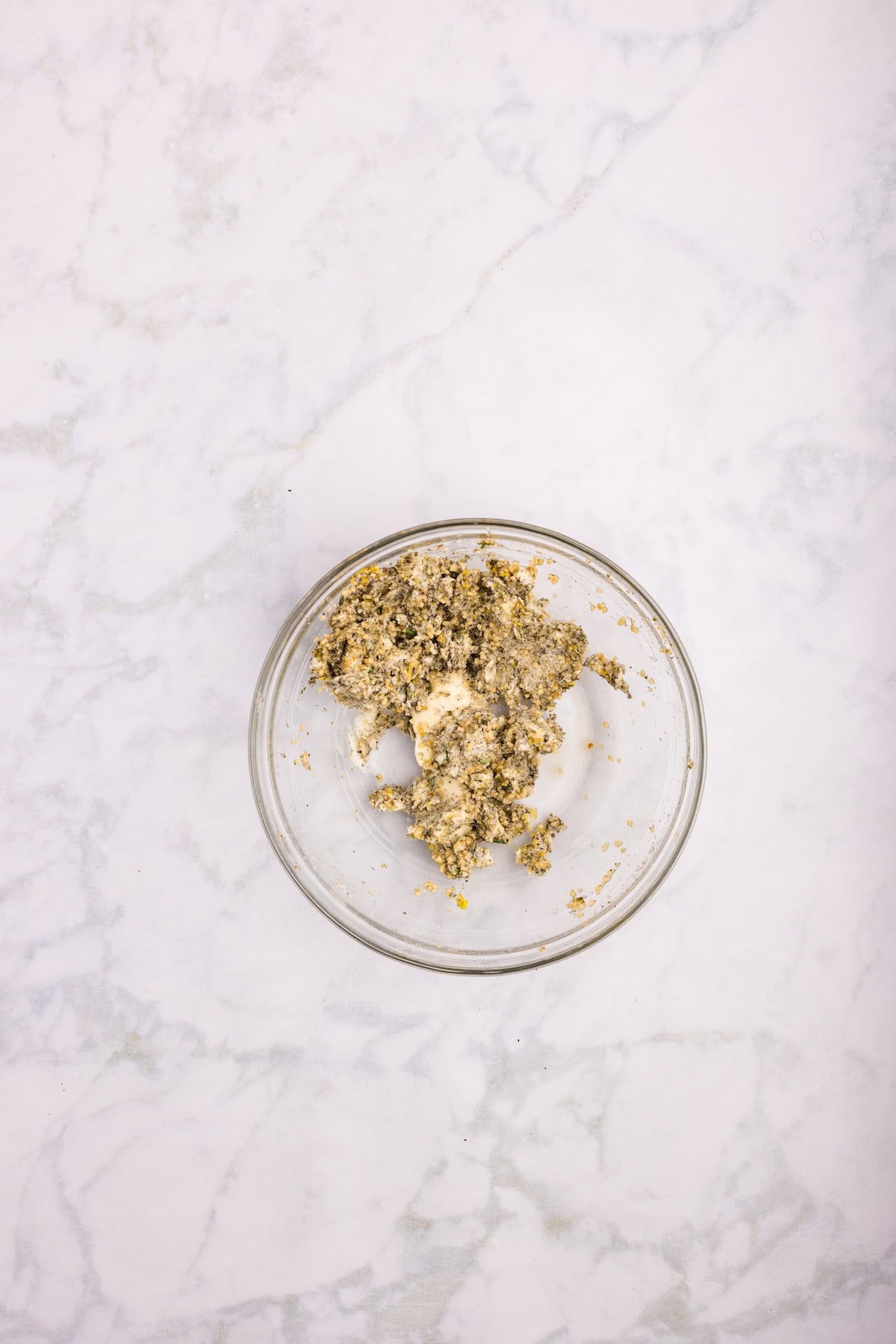 Softened butter mixed with garlic, rosemary, thyme, sage, and lemon zest in a small bowl for seasoning the bone-in turkey breast.
