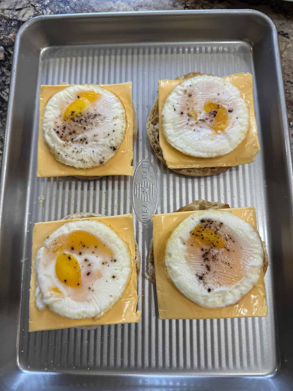 English muffins with cheese slice and cooked egg.