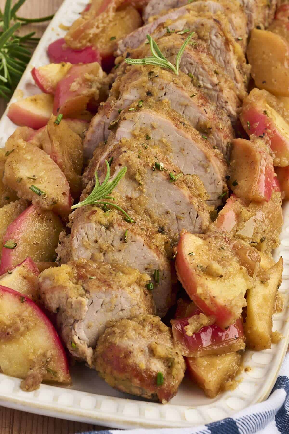 Honey-glazed pork tenderloin with roasted apples on a serving platter, perfect for a fall dinner.