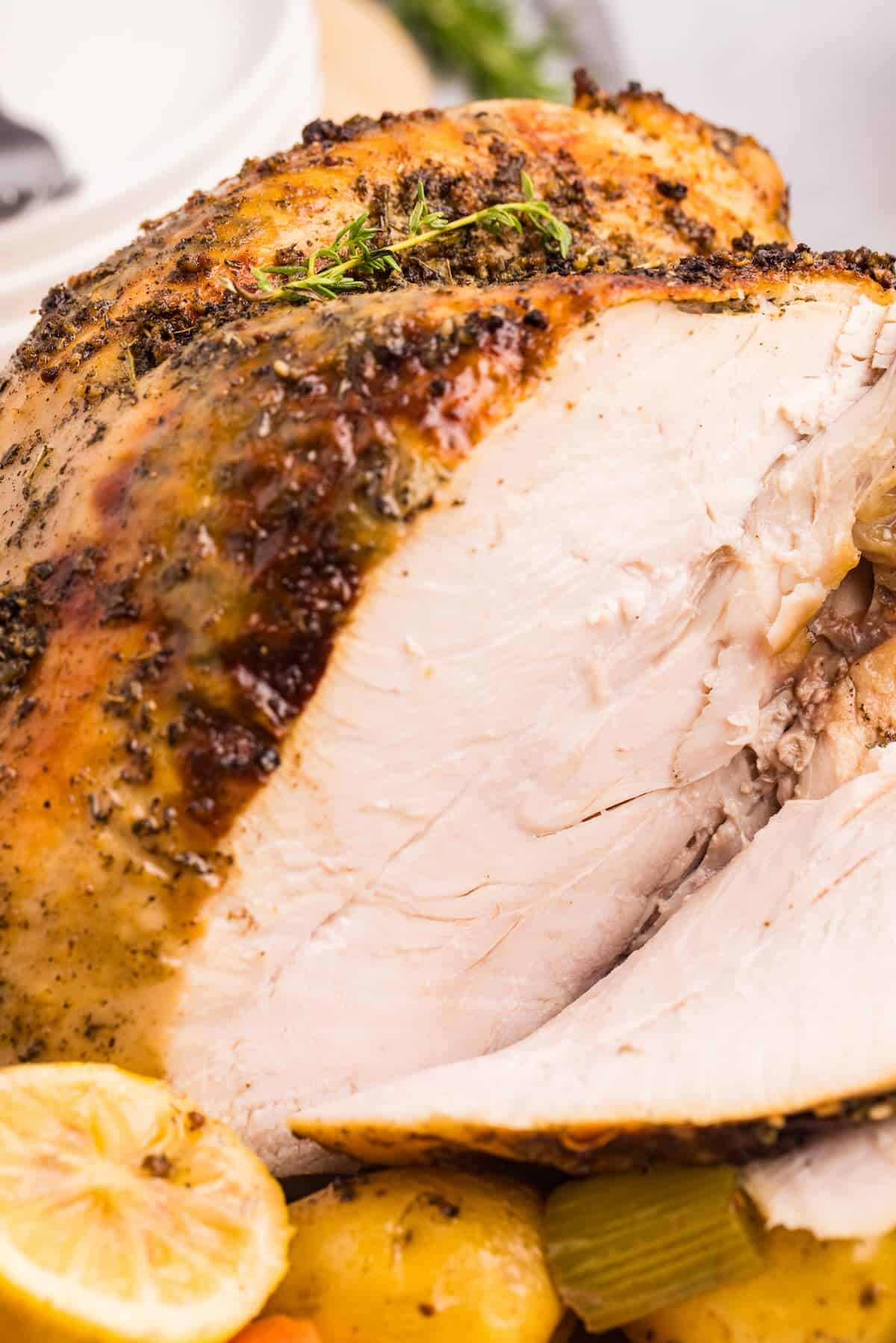 Sliced bone-in turkey breast served alongside roasted vegetables for a holiday-style dinner.