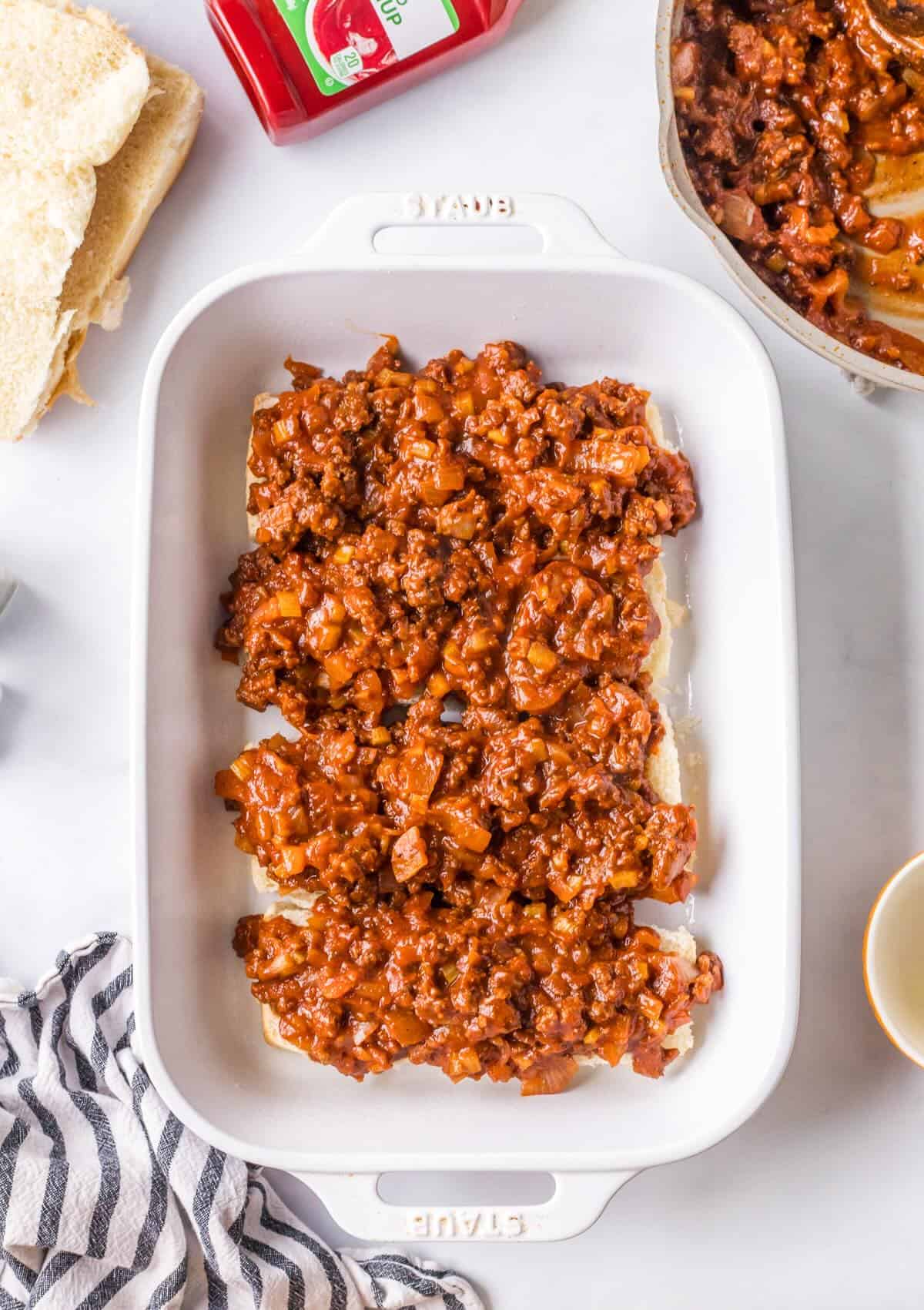 Layering ground beef filling and on Hawaiian rolls.