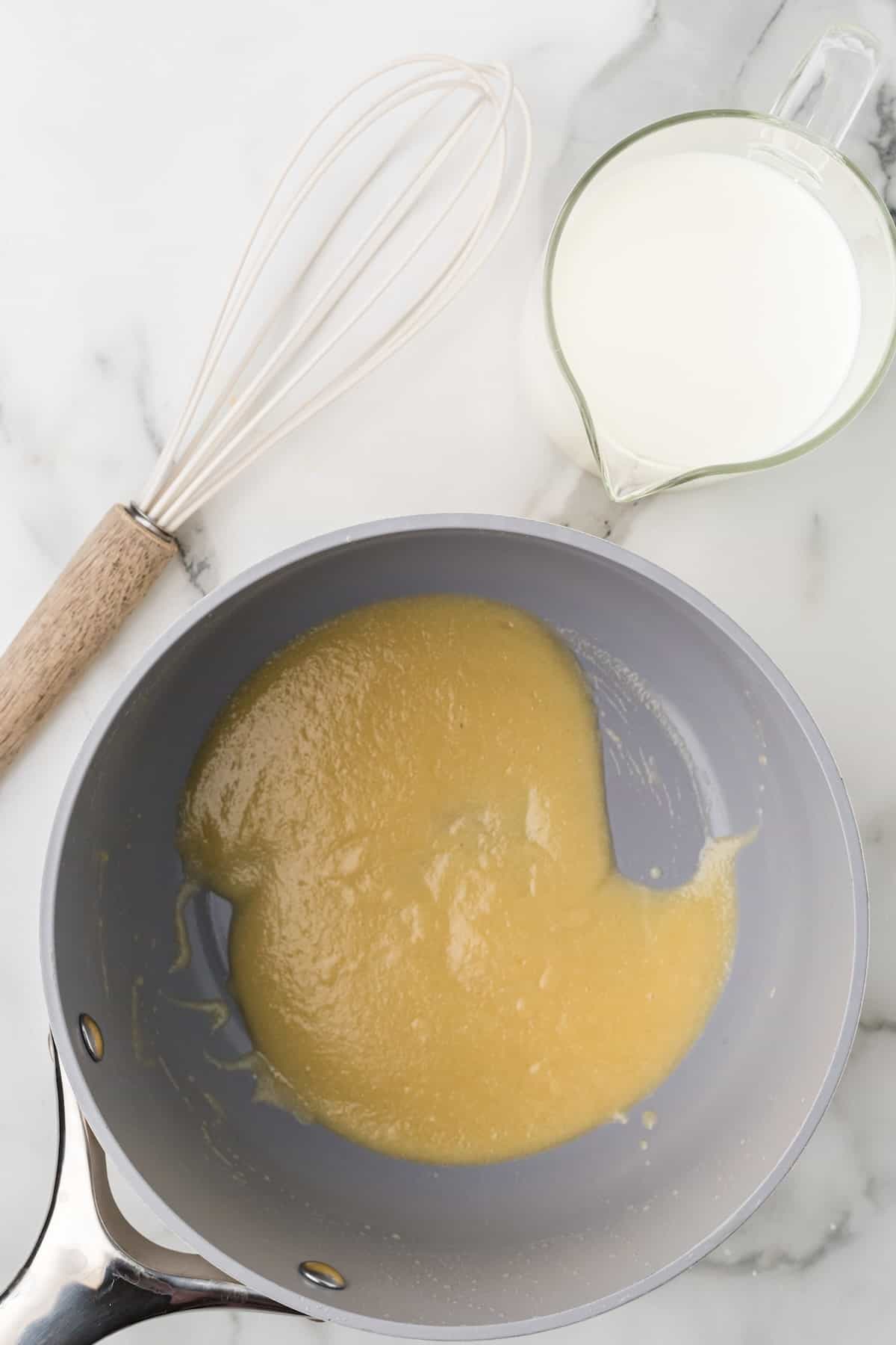 Whisking melted butter and flour together to create a roux for scalloped potatoes with cheese.