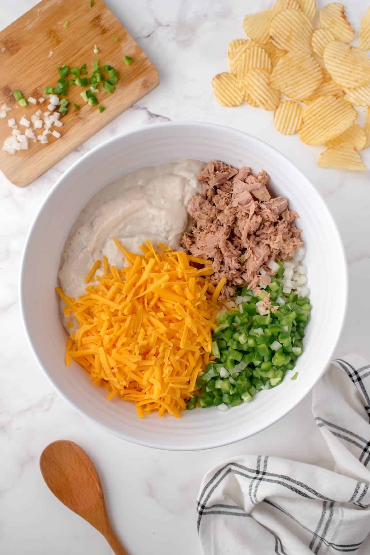 Mixing cream of mushroom soup, milk, tuna, and cheese in a large bowl.