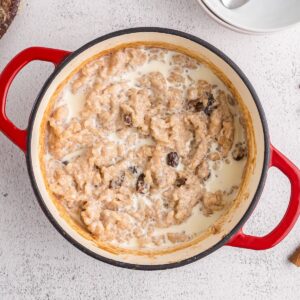 A Dutch oven full of old fashioned rice pudding with raisins and a splash of milk.