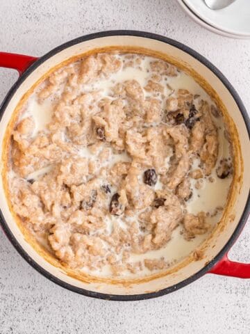 A Dutch oven full of old fashioned rice pudding with raisins and a splash of milk.