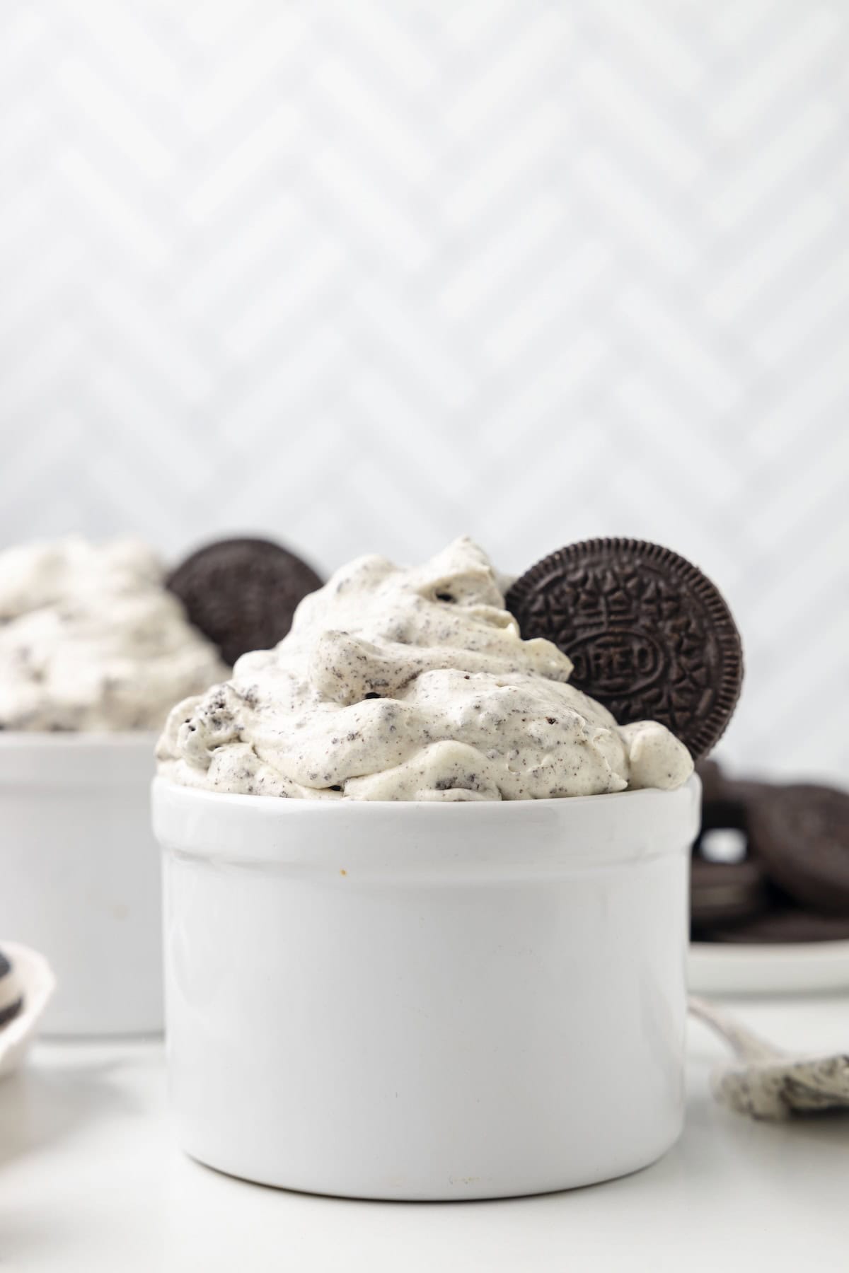 A bowl of creamy no bake oreo fluff with a cookie sticking out of the top.