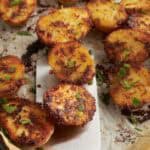 Spatula lifting crispy Parmesan crusted potatoes from baking sheet.