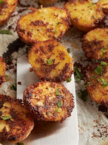 Spatula lifting crispy Parmesan crusted potatoes from baking sheet.