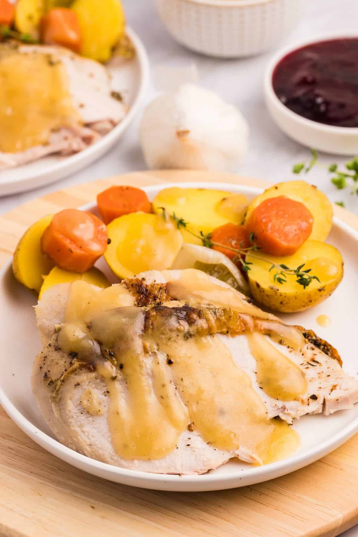 A plated Thanksgiving dinner with roast turkey and pan gravy with vegetables.