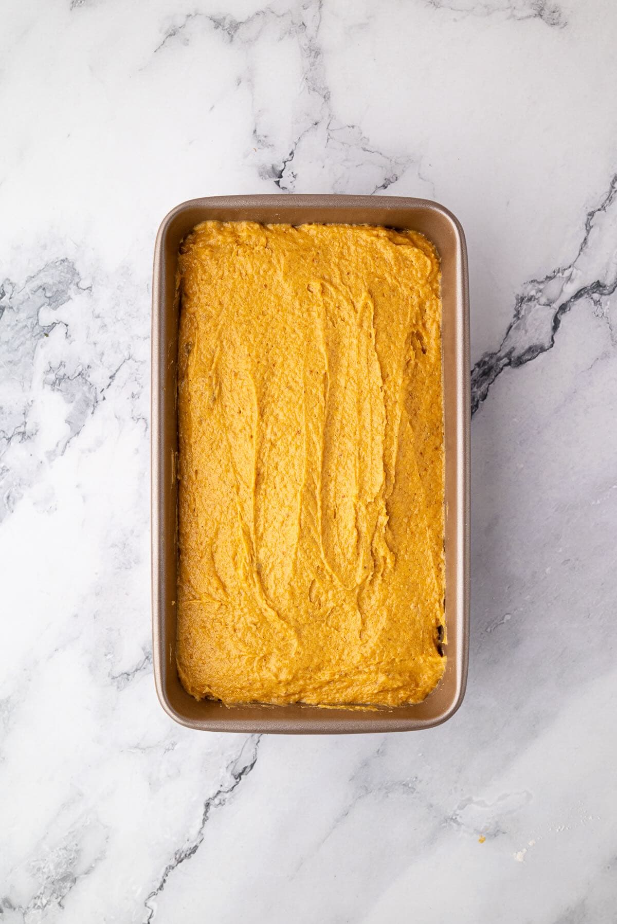 Pumpkin banana bread batter in a greased loaf pan before baking.