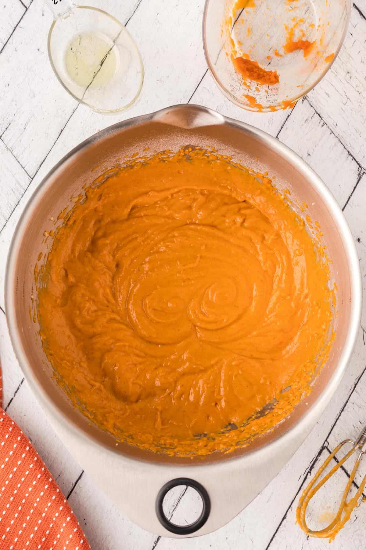Mixing pumpkin snack cake batter with a spatula until smooth and fluffy.