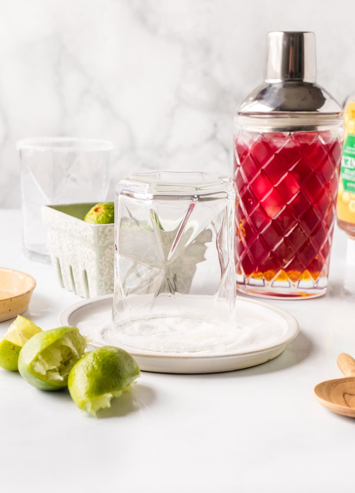 Rimming a glass with lime juice and sugar to make a festive cranberry lime margarita mocktail.