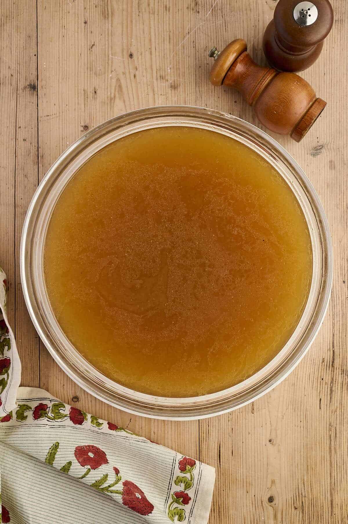 A bowl of warm chicken stock for use in soups or for freezing.