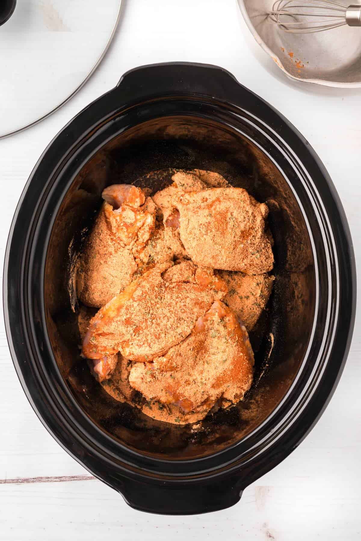 Seasoned chicken in the crock pot before cooking.