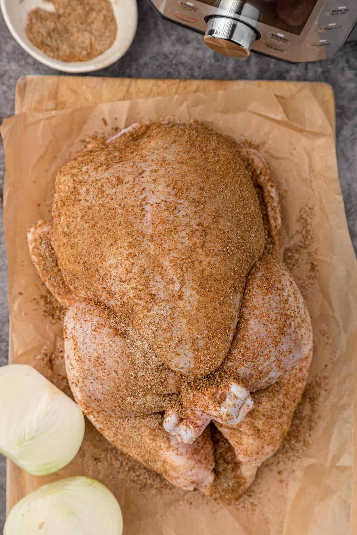 Rubbing seasoning and olive oil on a raw whole chicken before cooking.